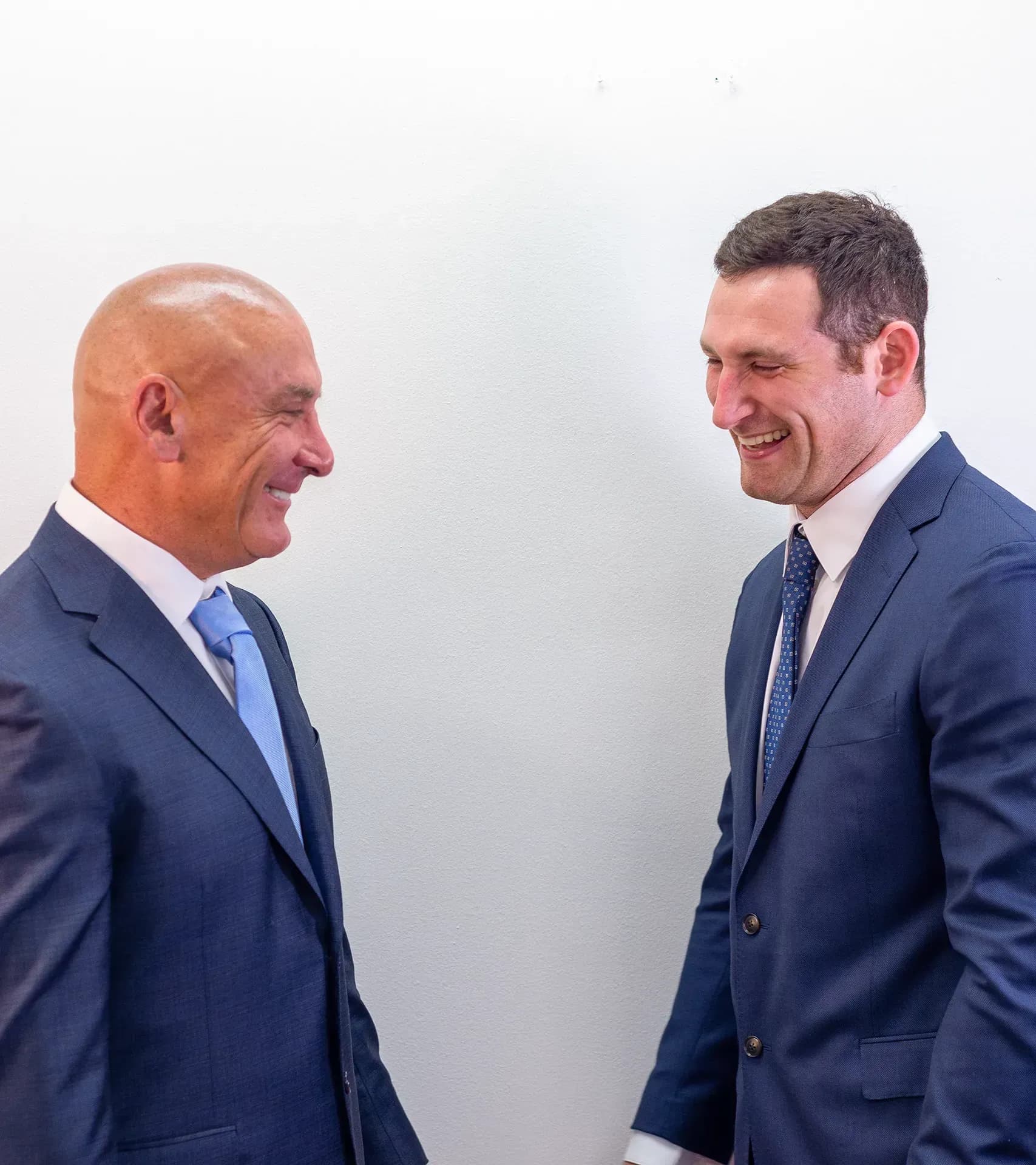 Personal injury lawyers Scott and Alex Senft facing each other and smiling cheerfully.