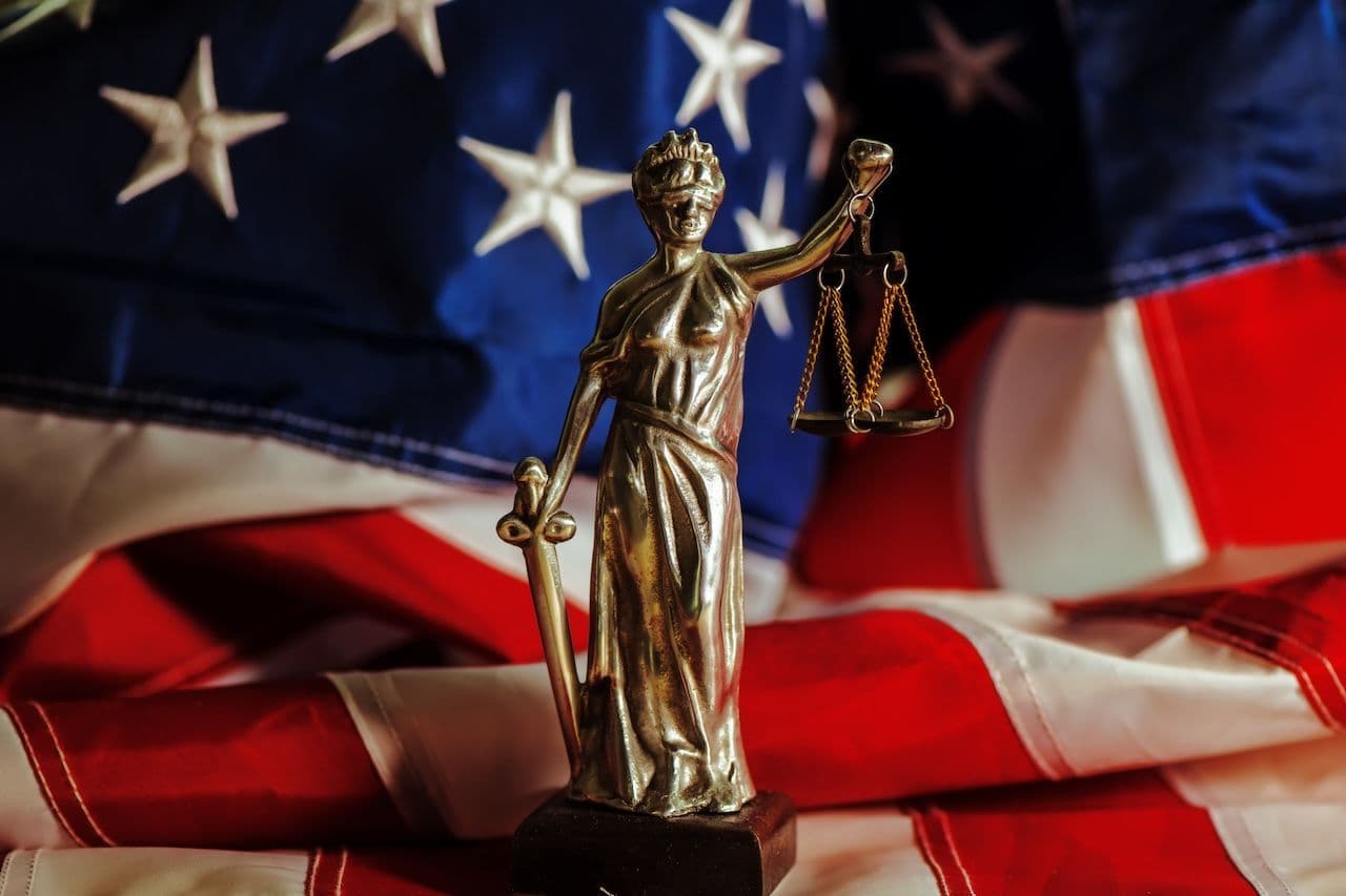 A statue of lady justice in front of the American flag; tort law is one of the key elements of the U.S. justice system.