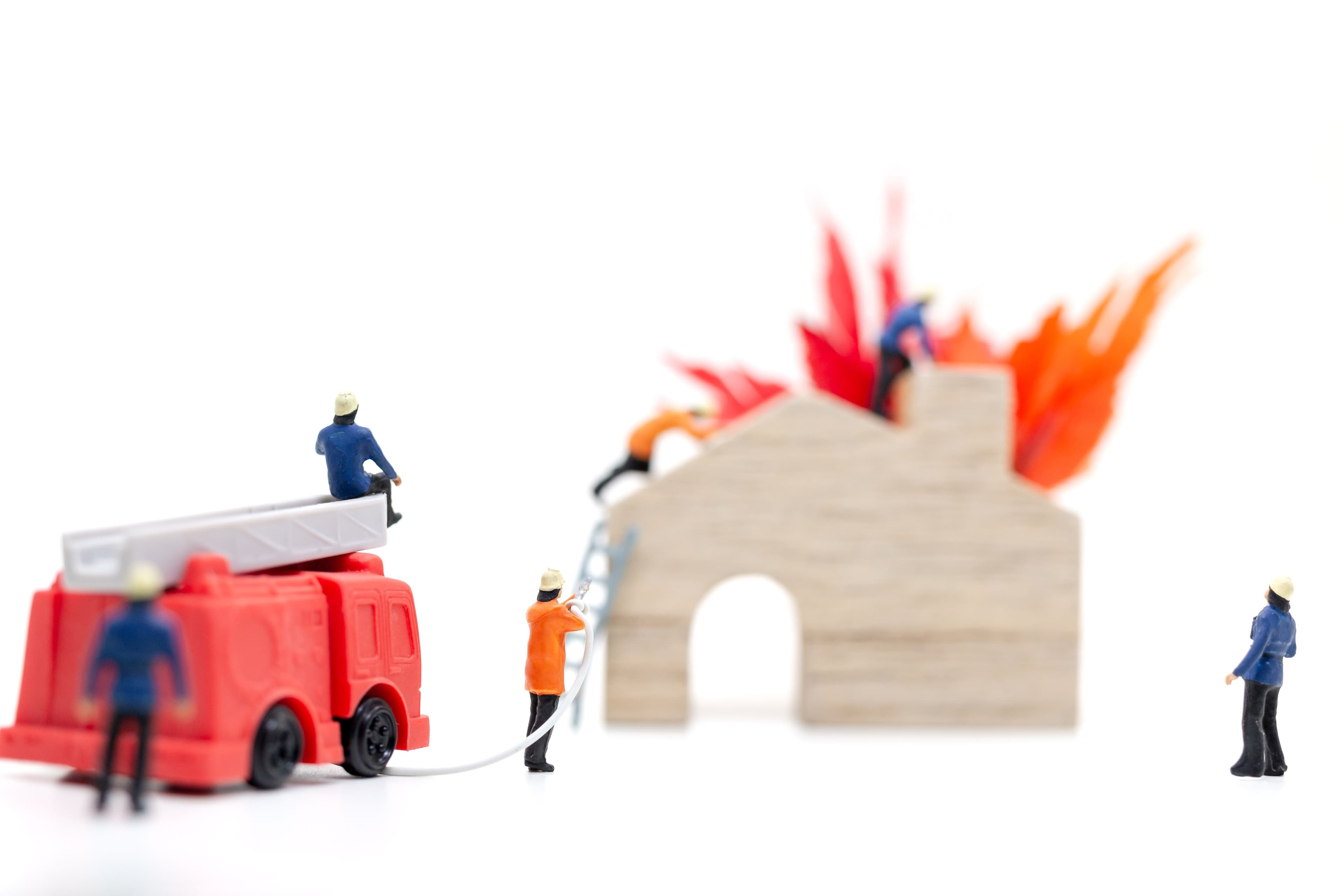 Toy figures putting out a house fire—this scenario is make-believe, but in real life, the potential devastation leads to the need for fire damage insurance claim help.