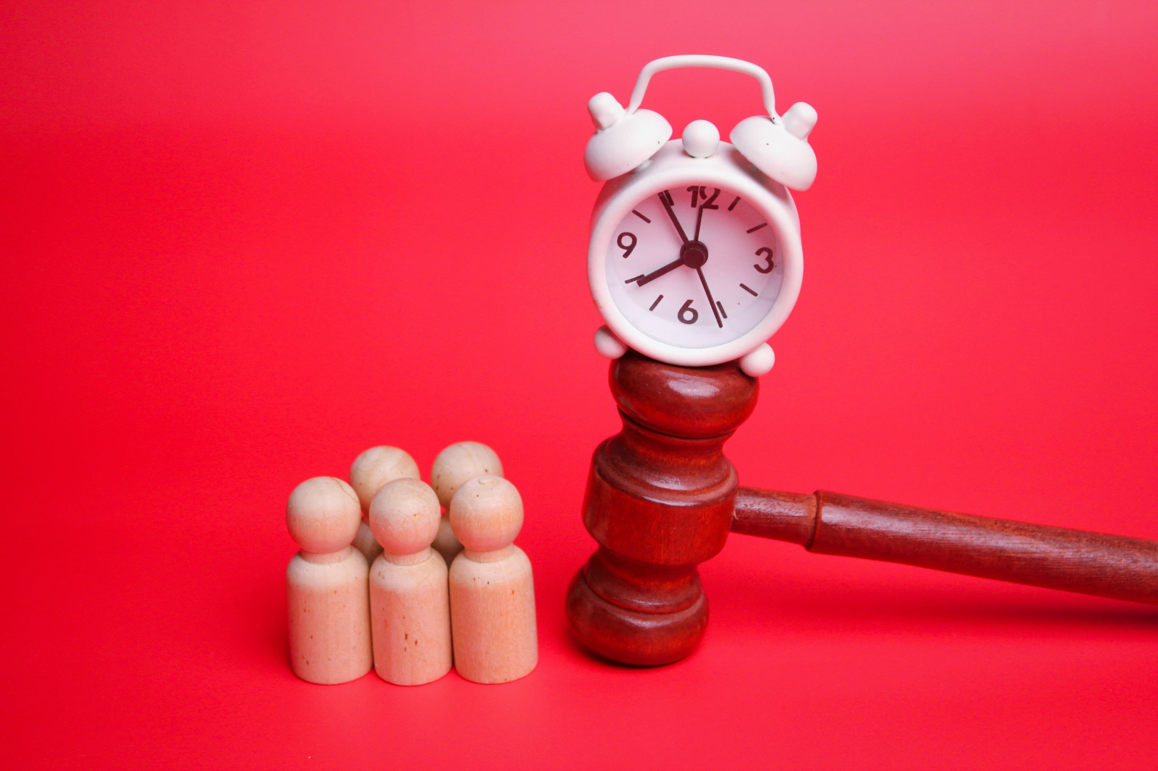 A gavel with a clock on top of it next to wooden figures, illustrating Oregon’s statute of limitations for personal injury.